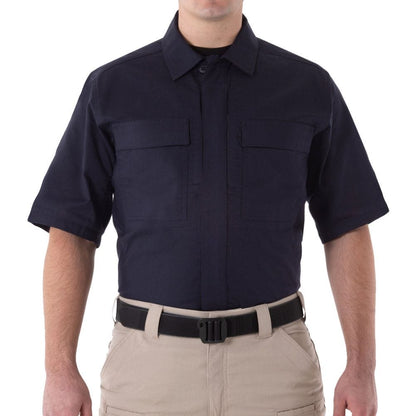Person wearing a navy short-sleeve shirt and beige pants on a white background